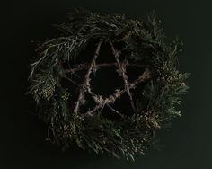 a circular wreath made out of branches and pine cones on a dark background with copy space in the center