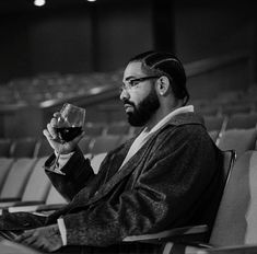 a man sitting in an auditorium holding a glass of wine