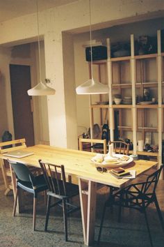 a dining room table with chairs and shelves in the background