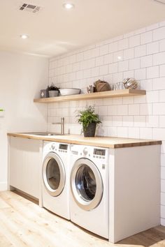 a washer and dryer in a room with white tiles on the wall,