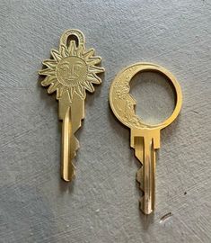 two keys that have been placed next to each other on a table, one has a sun and the other has a face