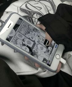 a person holding an electronic device in their hand with comic pages on the screen and ear buds attached to it