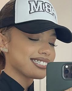 a woman taking a selfie in front of her cell phone wearing a black and white hat