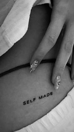 a woman's stomach with the words self made tattooed on her left side belly