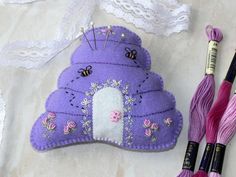 a purple purse with flowers on it next to some thread