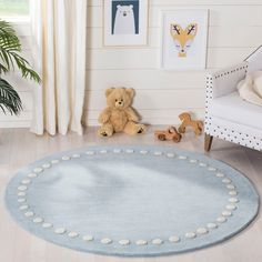 a teddy bear sitting on top of a rug in a living room next to a chair