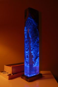 a blue light that is sitting on top of a table next to some books and a lamp