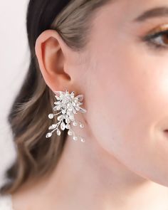 Perfect for adding a whimsical touch to any special occasion look, our Neve Floral Earrings bring a fresh take on timeless glamour. You'll have everyone commenting on these floral inspired statement earrings. Details: Hand wired with mix of light ivory pearls, rhinestones and tulle petals. Made with top grade rhinestones for ultimate sparkle. Specifications: 2" in length x 1.25" wide. Extremely lightweight and easily worn all day and evening. Tarnish Resistant: Earrings are tarnish resistant for Elegant Clip-on Flower Earrings For Party, Elegant White Clip-on Chandelier Earrings, Glamorous Wedding Flower Earrings For Pierced Ears, Delicate Pearl Earrings For Party, White Clip-on Bridal Earrings For Party, White Crystal Clip-on Earrings For Party, Party Pearl Drop Flower Earrings, Silver Pearl Drop Flower Earrings, White Cluster Earrings With Pearl Drop For Party