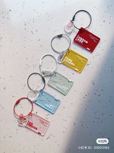 four different colored plastic keychains on top of a white surface with water droplets