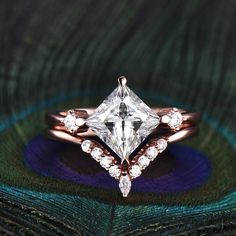 a close up of a ring with a diamond on it and a peacock feather in the background