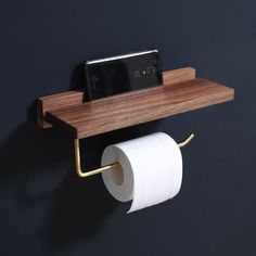 a cell phone is sitting on a wooden shelf next to a roll of toilet paper