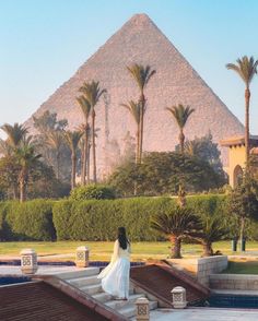 a woman sitting on steps in front of a pyramid