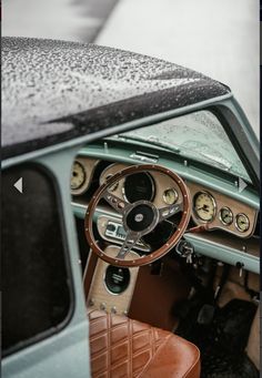 the interior of an old car is covered in raindrops and has brown leather seats