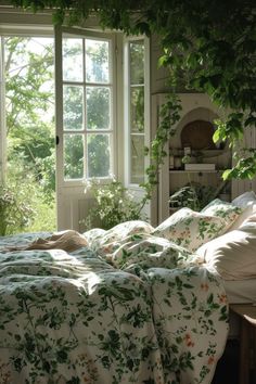 an unmade bed sitting in front of a window next to a plant filled wall