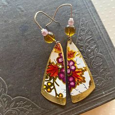 the earrings are decorated with flowers and leaves on them, along with beaded earwires