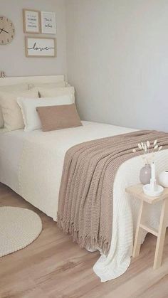 a bedroom with a white bed and beige blankets on top of the bedspread