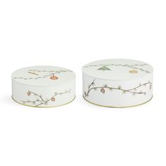 two white boxes with pine cones and branches painted on the sides, one is empty