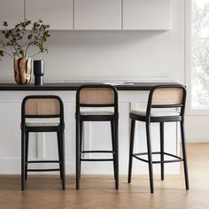 two chairs and a table in a room with white walls, hardwood flooring and cabinets