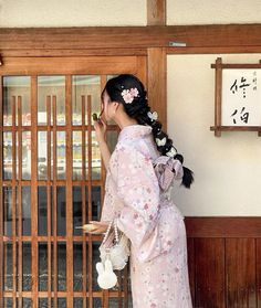 a woman in a pink kimono is standing by a door and holding a tea pot