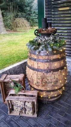 a wooden barrel sitting on top of a brick floor next to a box filled with christmas decorations