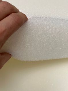 a hand is holding the edge of a foam mattress