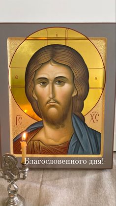 the icon of jesus christ is on display in front of a candle and some candles