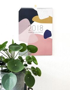 a potted plant next to a calendar on a wall