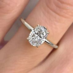 a woman's hand with a diamond ring on top of her finger, showing the center stone