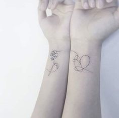 two wrist tattoos with hearts and flowers on each arm, one is holding the other's hand