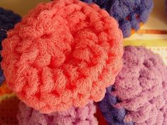 several crocheted items are arranged on a table top, including one pink and one blue