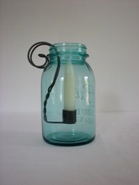 a blue glass jar with a candle in it sitting on a white tableclothed surface