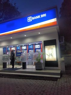 a man standing in front of a bank building at night with his hands on his hips