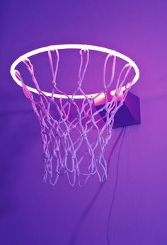 a neon basketball hoop hanging from the side of a purple wall with wires attached to it