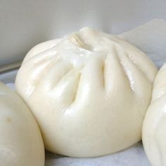 three dumplings sitting on top of a pan covered in wax paper