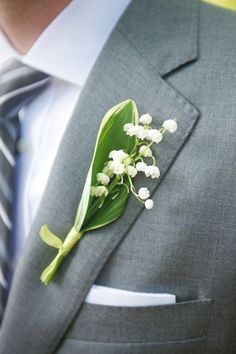 a boutonniere with lily of the valley on it is worn by a man in a suit