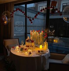 a table with candles and flowers on it in front of a window