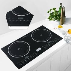 an electric cooktop sits on a white counter top next to a vase with flowers