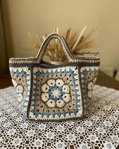 a crocheted bag sitting on top of a table next to a flower vase