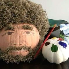 a man with a beard and mustache is next to a pumpkin that has been painted