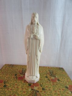 a white statue sitting on top of a table next to a green and yellow cloth