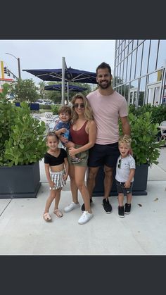 a man, woman and two children posing for a photo in front of some plants