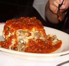 a white plate topped with lasagna covered in sauce