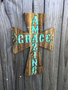 a wooden cross hanging on a fence with the word grace painted on it's side