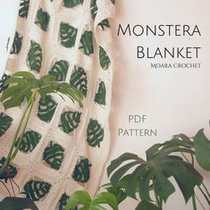 a crocheted blanket with green leaves on it next to a potted plant