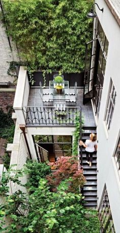 an aerial view of a patio with chairs and tables in the middle of it, surrounded by greenery