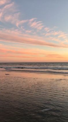 a person walking on the beach with a surfboard in their hand, at sunset