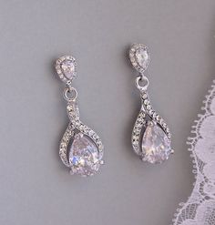 two pairs of white crystal earrings on a lace doily