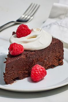 a piece of chocolate cake with whipped cream and raspberries