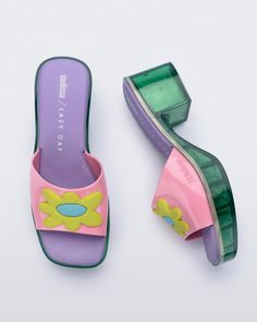 The favorite collab of recent times is making an exciting comeback. Melissa Shape + Lazy Oaf is full of nostalgia, inspired by the 90s and 2000s. The London brand is known for its bold colors, graphic designs, and subtle humor. The new clog-style model has the much-loved square toe alongside a low block heel. The daisies applied on the top are a joyful nod to the current trend. Daisy Shoes, 90s Accessories, Mini Melissa Shoes, 90s Stuff, London Brands, Clogs Style, Lazy Oaf