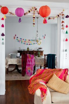 a living room filled with furniture and lots of paper lanterns hanging from the ceiling above